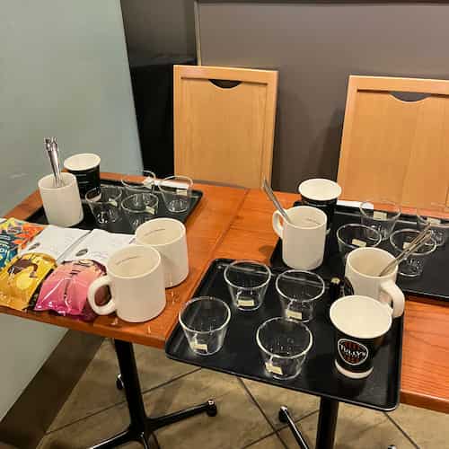 カッピング体験の用意がされたテーブル。プリンカップやマグカップ、コーヒー豆が置かれています。